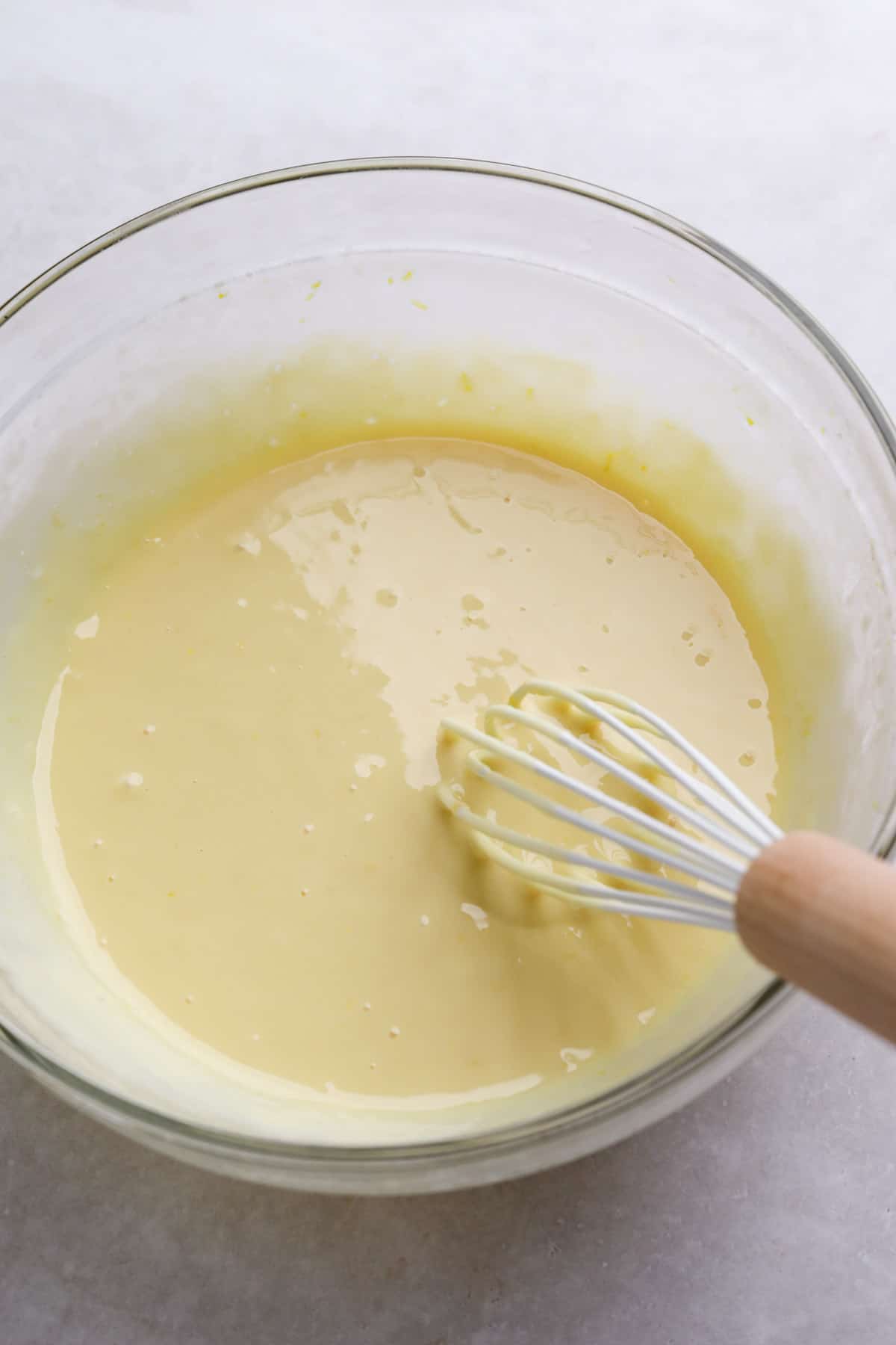 Close up of lemon bar filling mixed in a glass bowl with a whisk in the bowl.