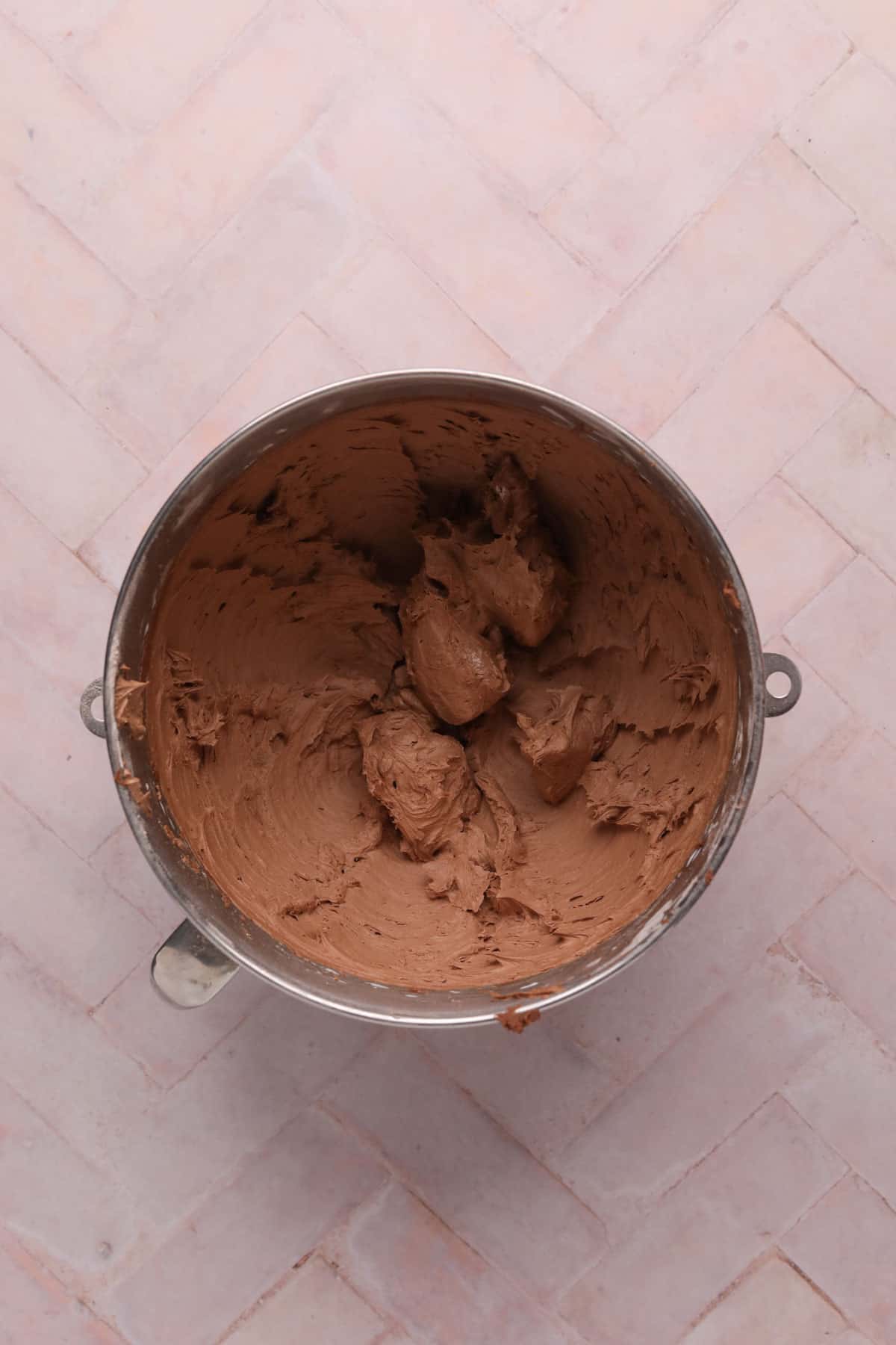Chocolate butter cream mixed in a stand mixer bowl.