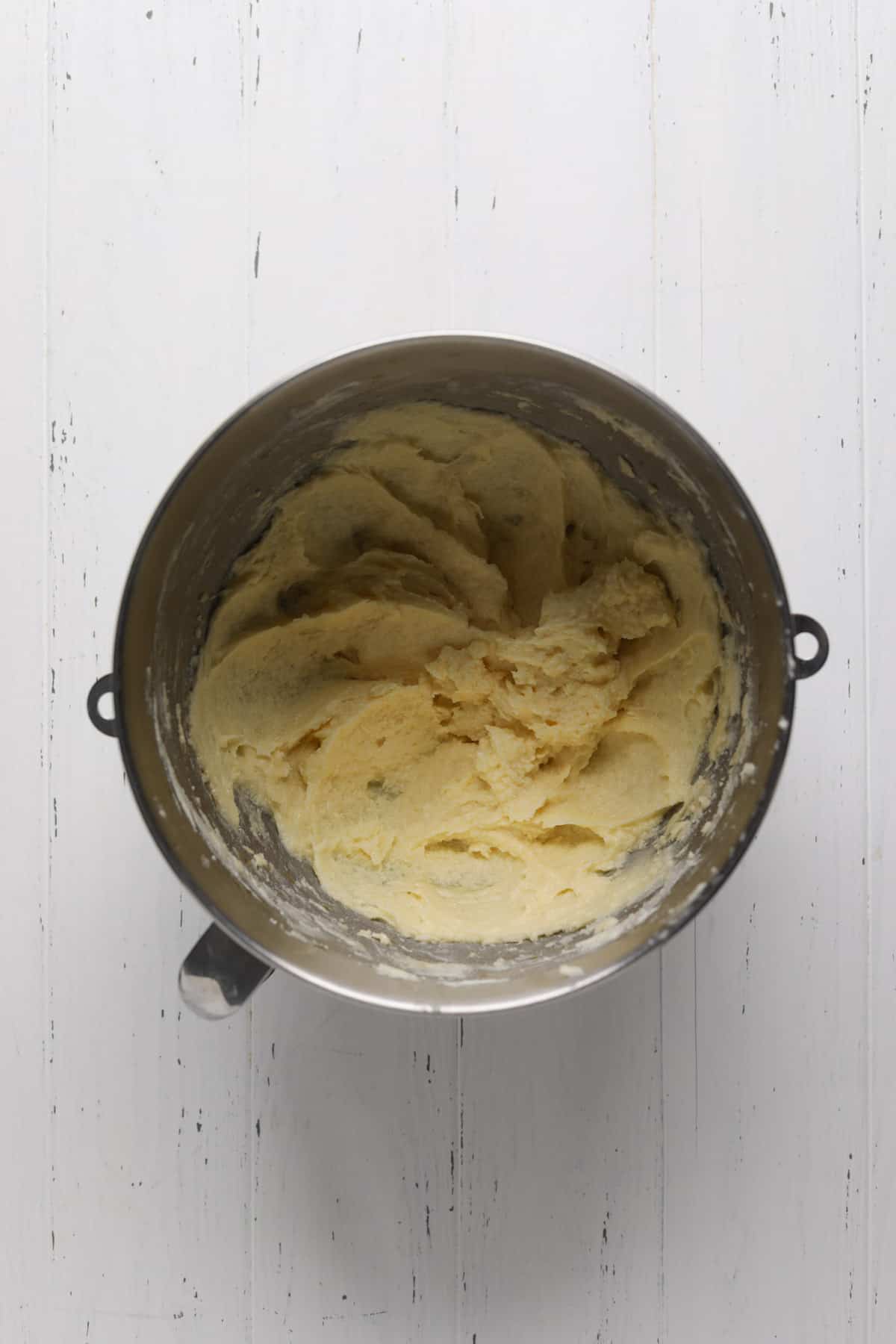 Creamed butter and sugar mixed with egg and vanilla in a stand mixer bowl.