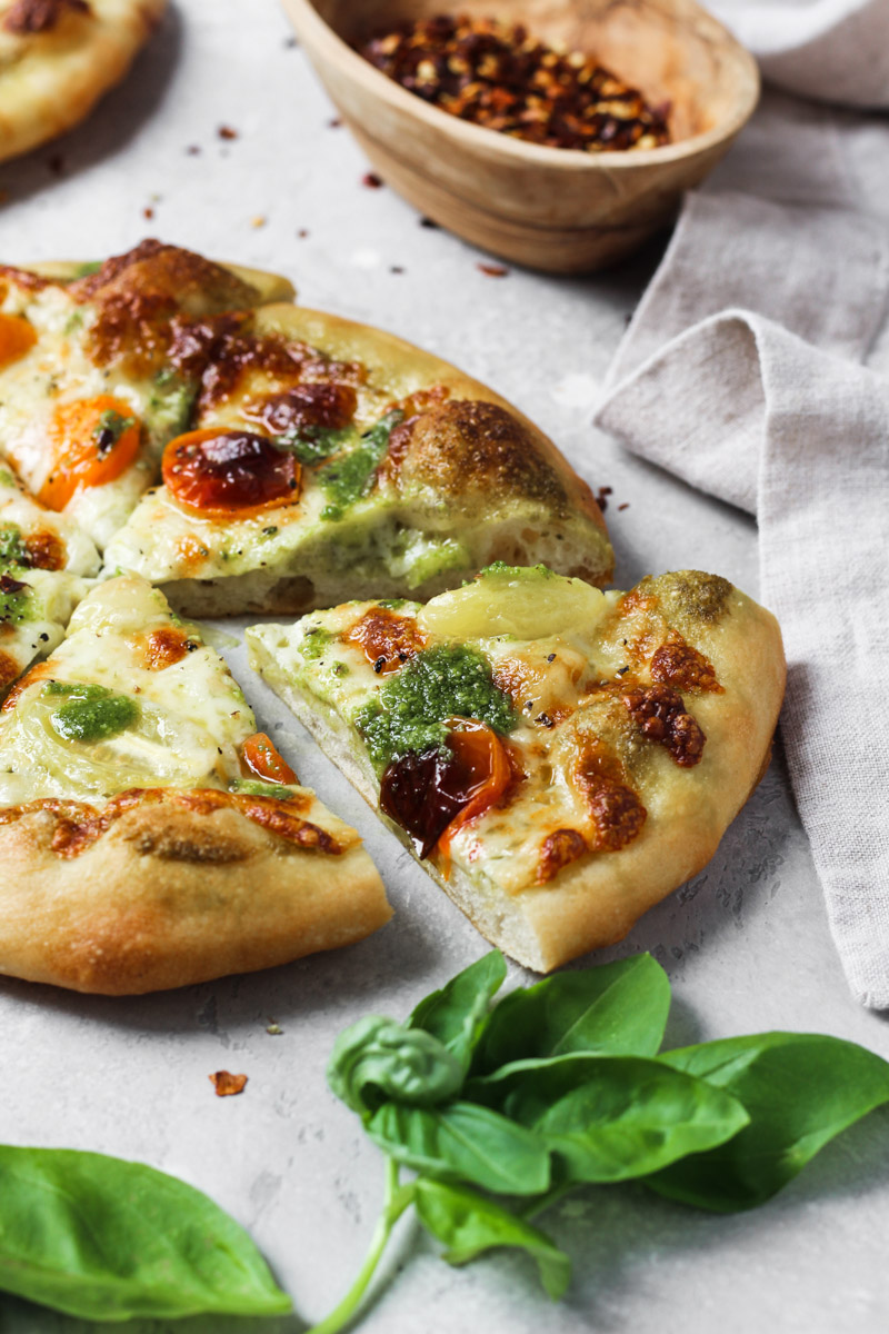 Individual basil pesto pizza sliced.