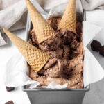 Container of No Churn Chocolate Brownie Ice Cream with three ice cream cones