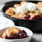 Bowl of cherry cobbler with cream biscuits and vanilla ice cream