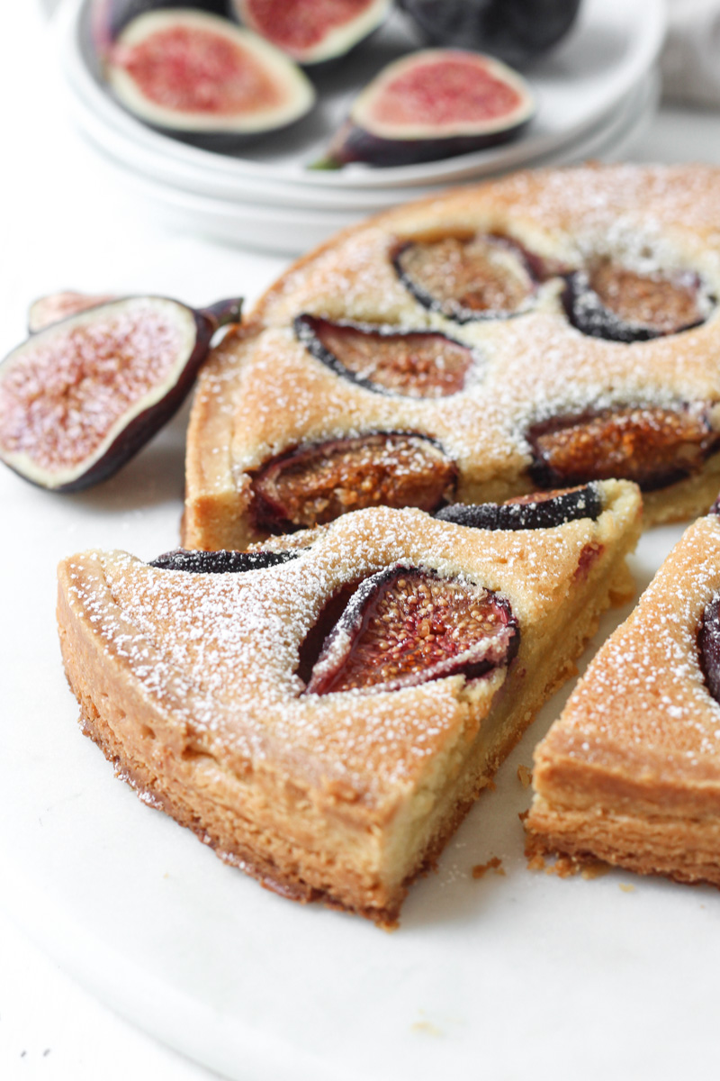 Side angle close up of fresh fig tart with almond cream filling and slice cut.