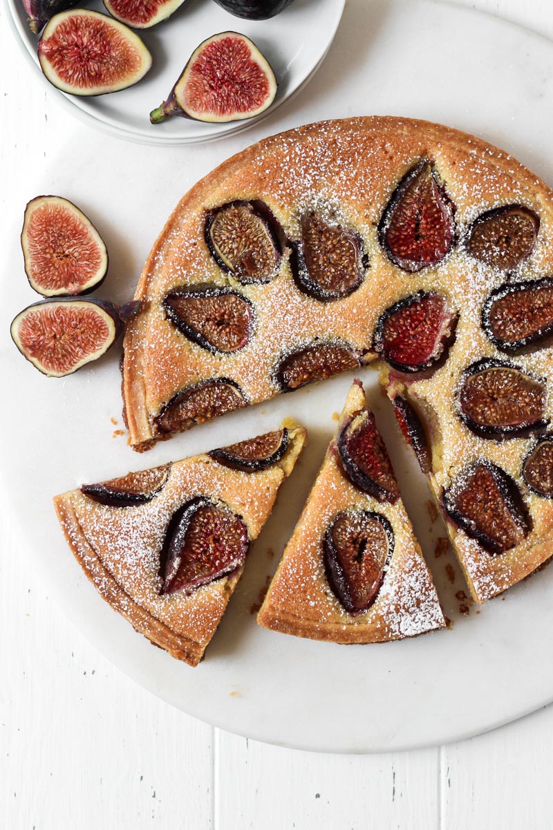 Looking down on fresh fig tart with an almond cream filling with two slice cut.