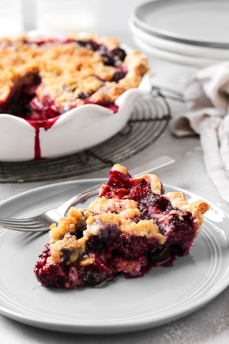 Slice of mixed berry pie with crumb topping.