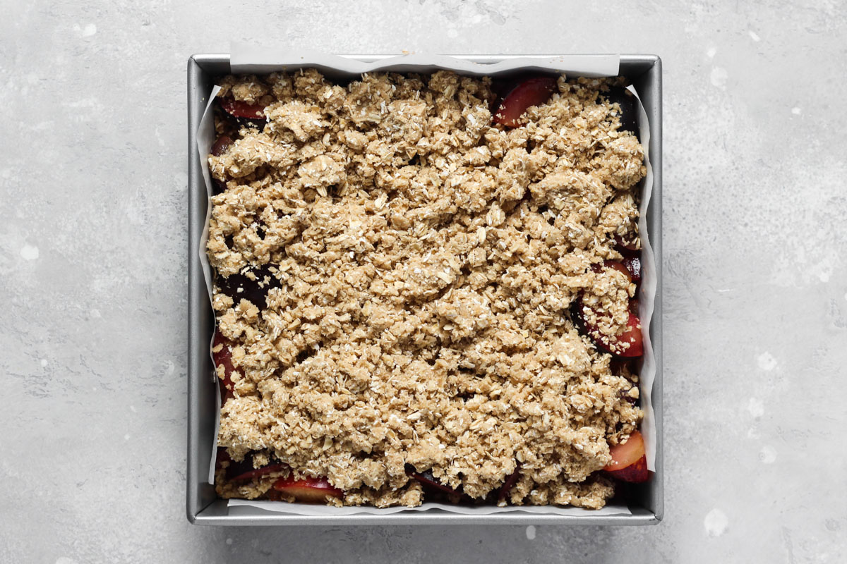 Unbaked plum bars in square baking pan.