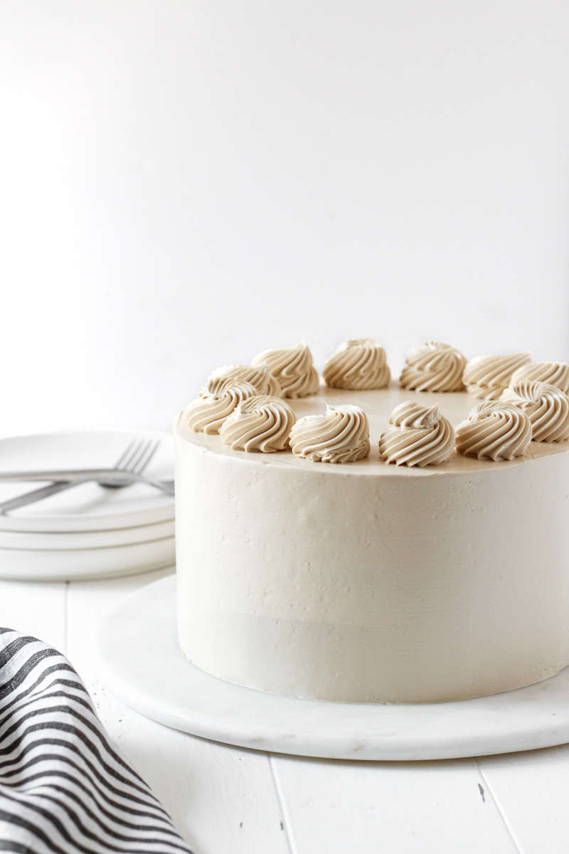 8-inch round apple cider cake with brown sugar Swiss meringue buttercream with rosettes on top.