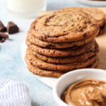 Stack of cookie butter cookies with bowl of cookie butter and glass of milk.