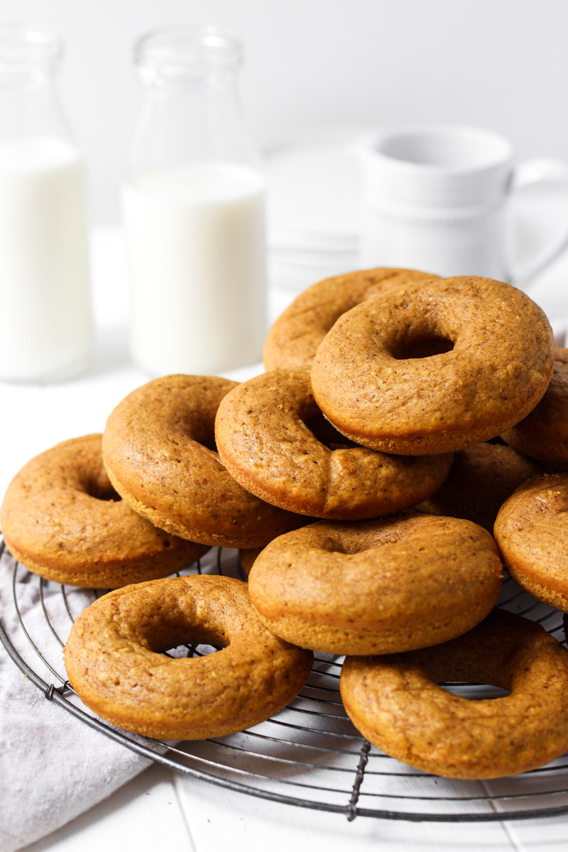 Stack of baked pumpkin donuts on a round French wire rack.