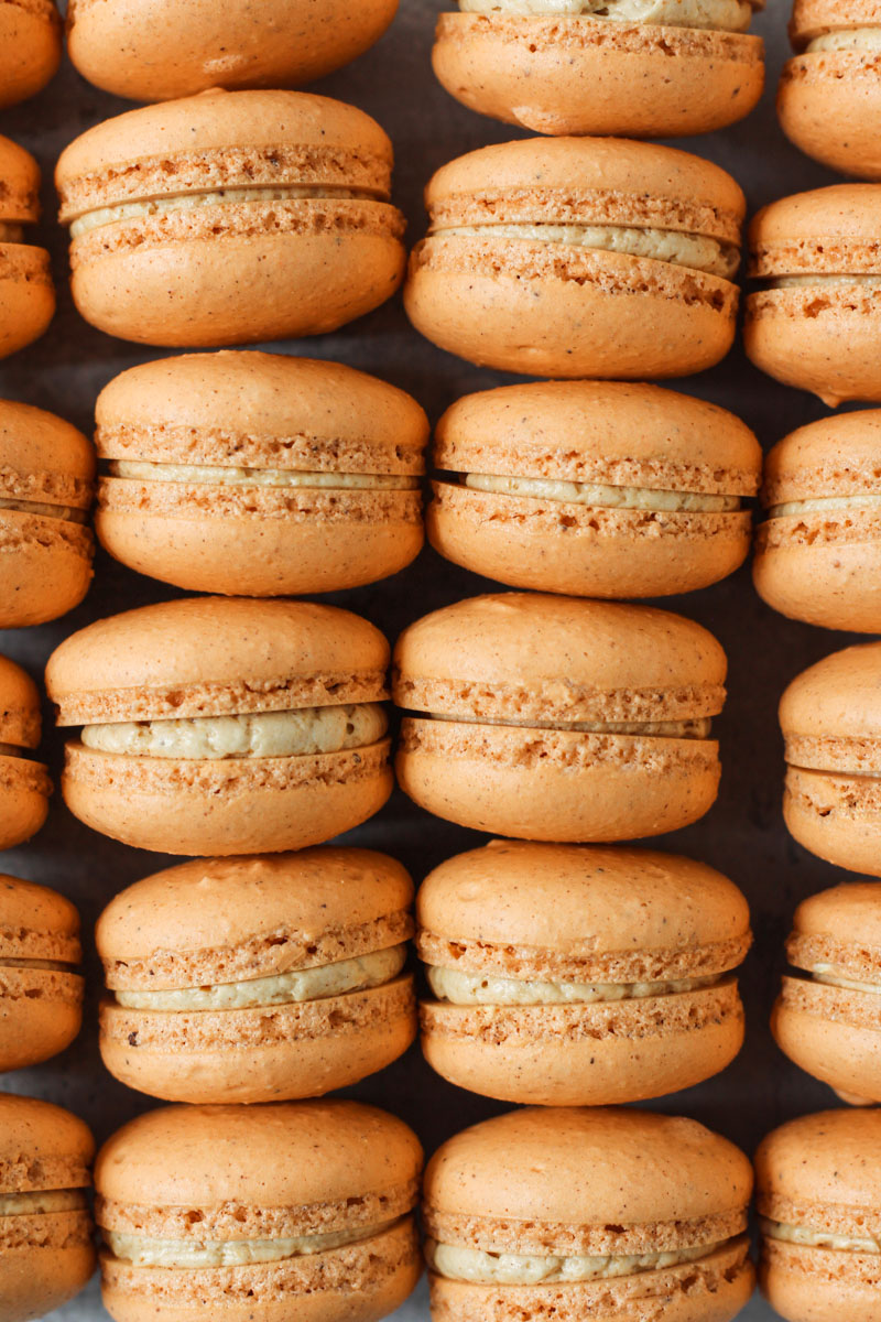 Overhead shot of columns of pumpkin macarons filled with pumpkin Swiss meringue buttercream.