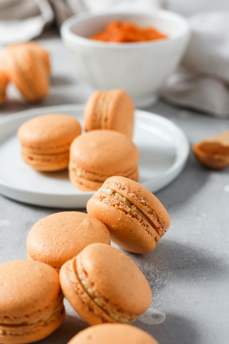 Spread of pumpkin macarons filled with pumpkin Swiss meringue buttercream.