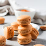 Stack of pumpkin macarons with pumpkin Swiss meringue buttercream.