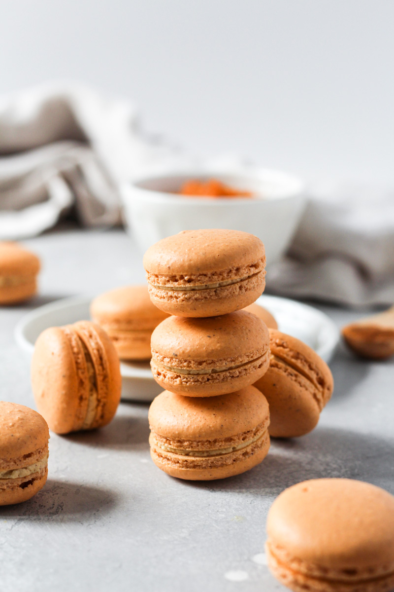 Stack of pumpkin macarons with pumpkin Swiss meringue buttercream.