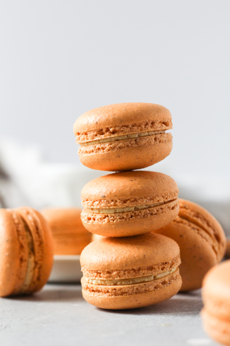 Stack of pumpkin macarons with pumpkin Swiss meringue buttercream.