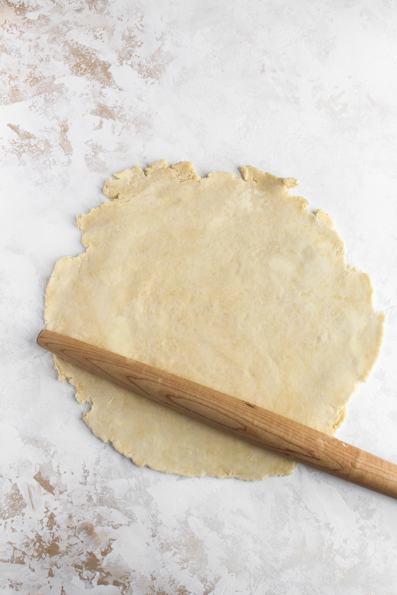 Rolled out all butter pie crust on a work surface with a French rolling pin.
