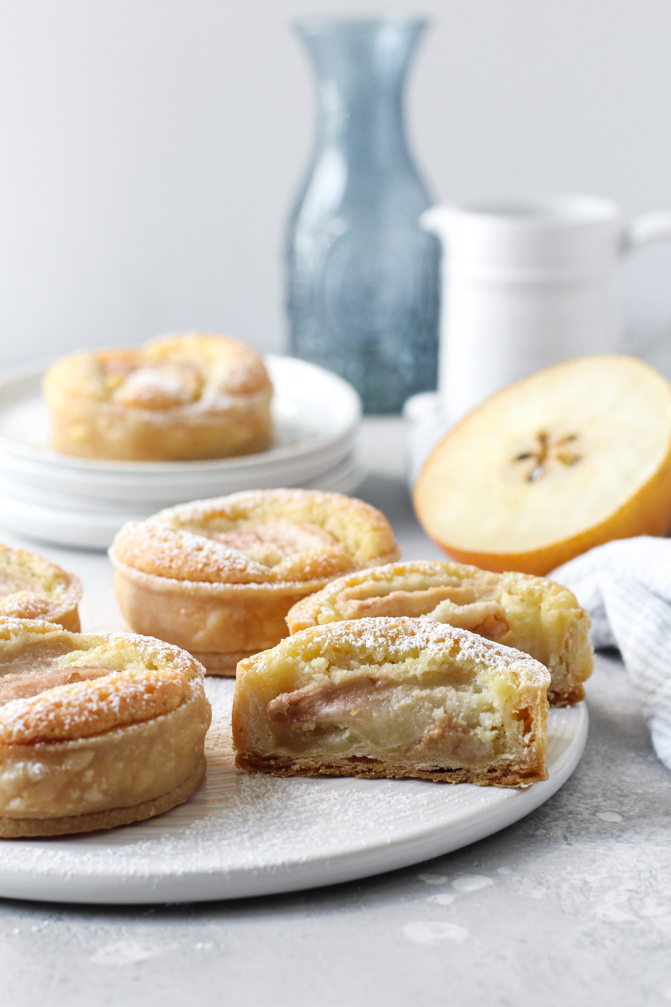 Plate of four individual Asia pear tars with a almond cream filling and one tart sliced in half displaying filling.