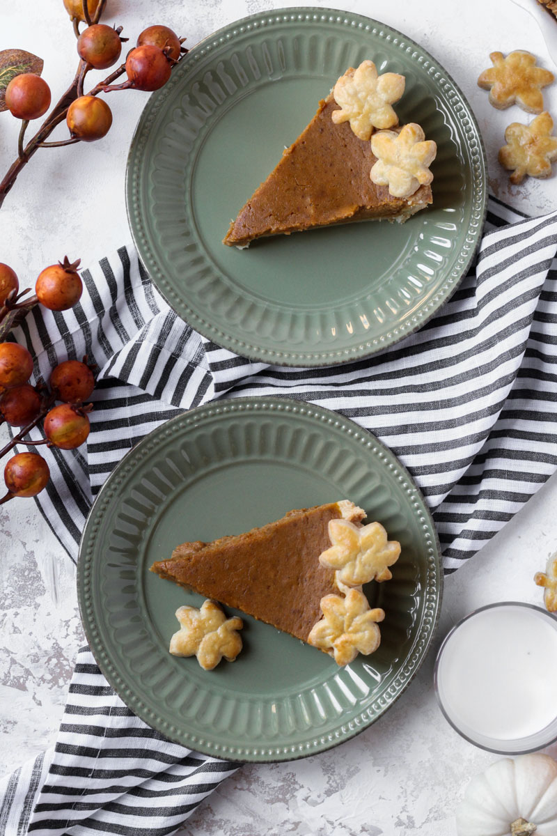 Two slices of brown butter pumpkin pie with pie crust leaf cutouts for a border.