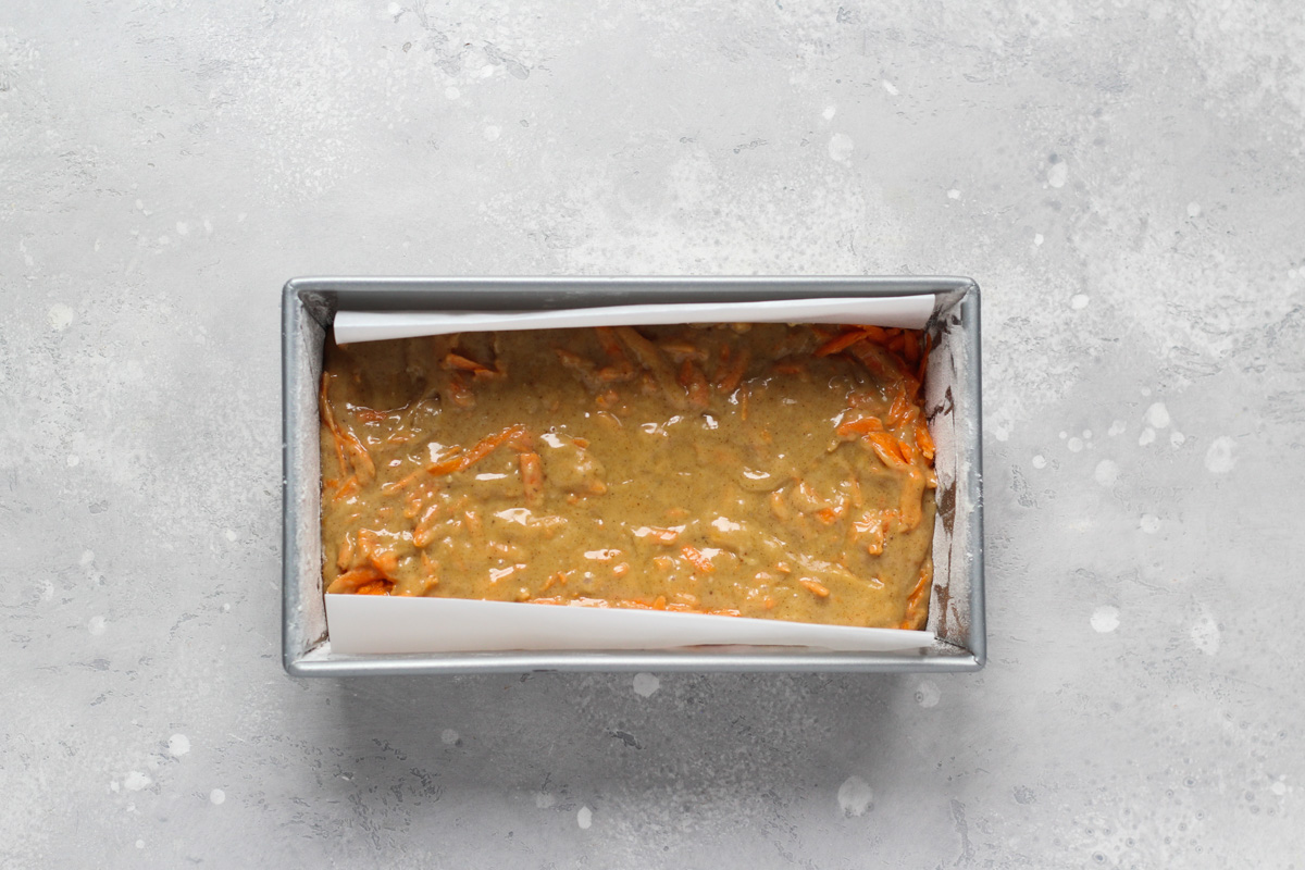 9x5 -inch baking pan lined with parchment paper and filled with carrot cake loaf batter.