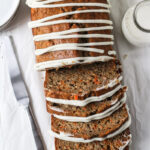 Overhead shot of carrot cake loaf sliced with zig zag drizzle of homemade cream cheese frosting.