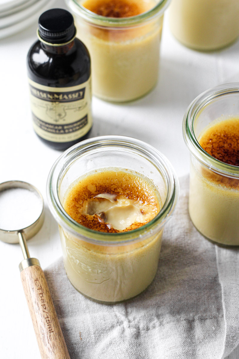 Jars of maple creme brulee with one displaying a cracked topped.