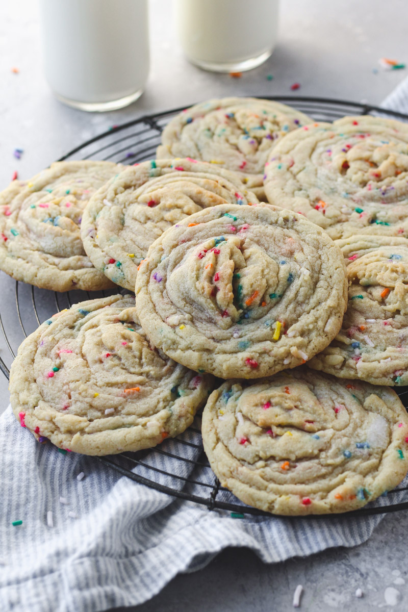 Stack of funfetti stuffed cookies with buttercream on a French wire rack.