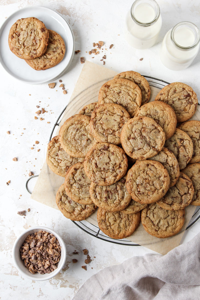 Overlooking stack of brown butter cookies with toffee tits on a round French wire cooling rack.