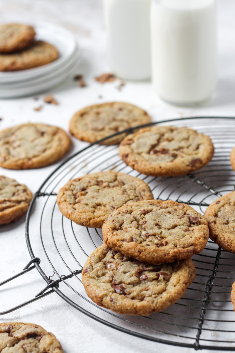 Brown butter cookies with toffee bits arranged on a round French wire cooling rack.