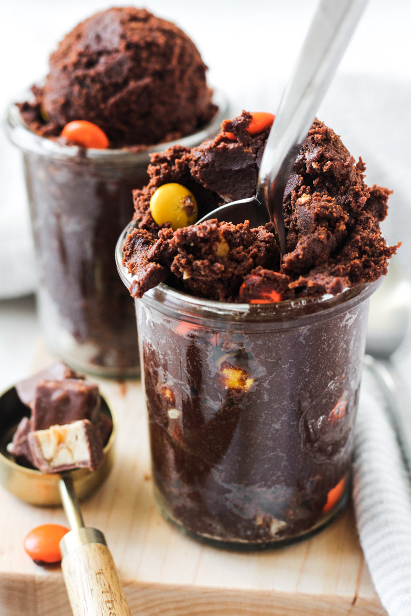 Edible chocolate cookie dough with mixed in candy in two glass jars.