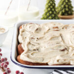 Pan with frosted gingerbread flavored cinnamon rolls in a baking pan with some cinnamon rolls.