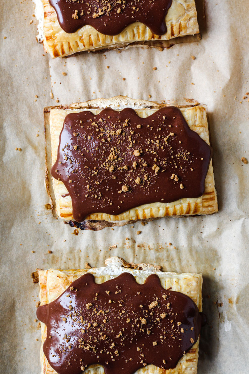 Overhead shot of homemade pop tart with pumpkin and marshmallow filling with a chocolate glass and gingersnap crumbs on baking sheet pan