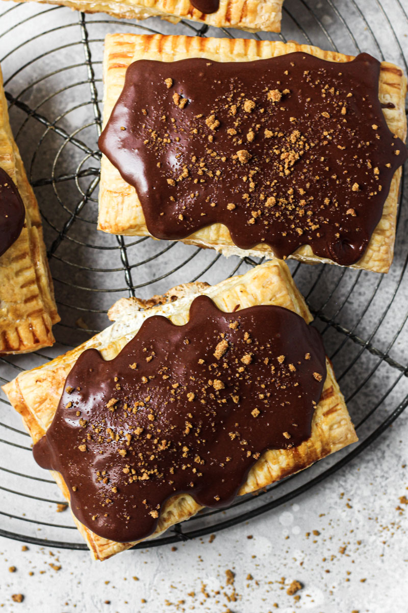 Overhead shot of homemade pop tart with pumpkin and marshmallow filling with a chocolate glass and gingersnap crumbs.