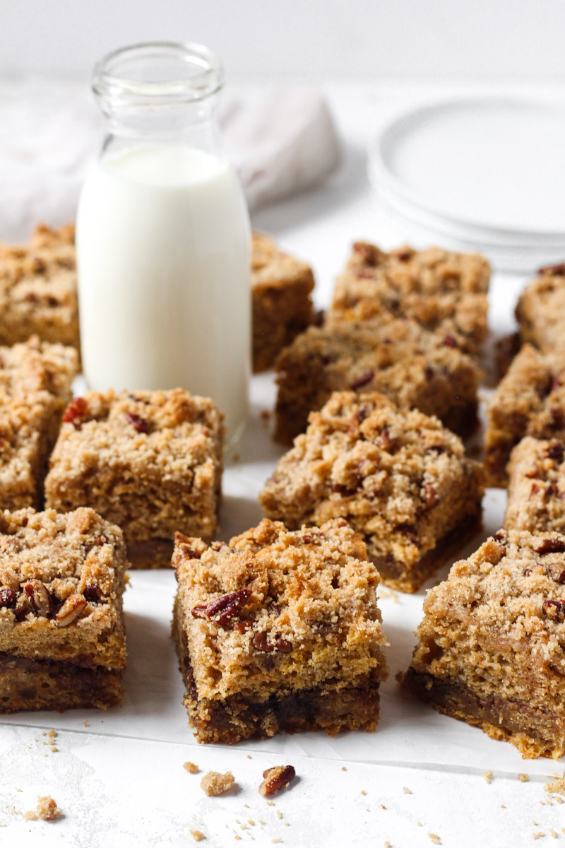 Coffee cake with a sweet potatoes, spiced brown sugar filling, and streusel topping sliced into squares and arranged with a glass of milk.