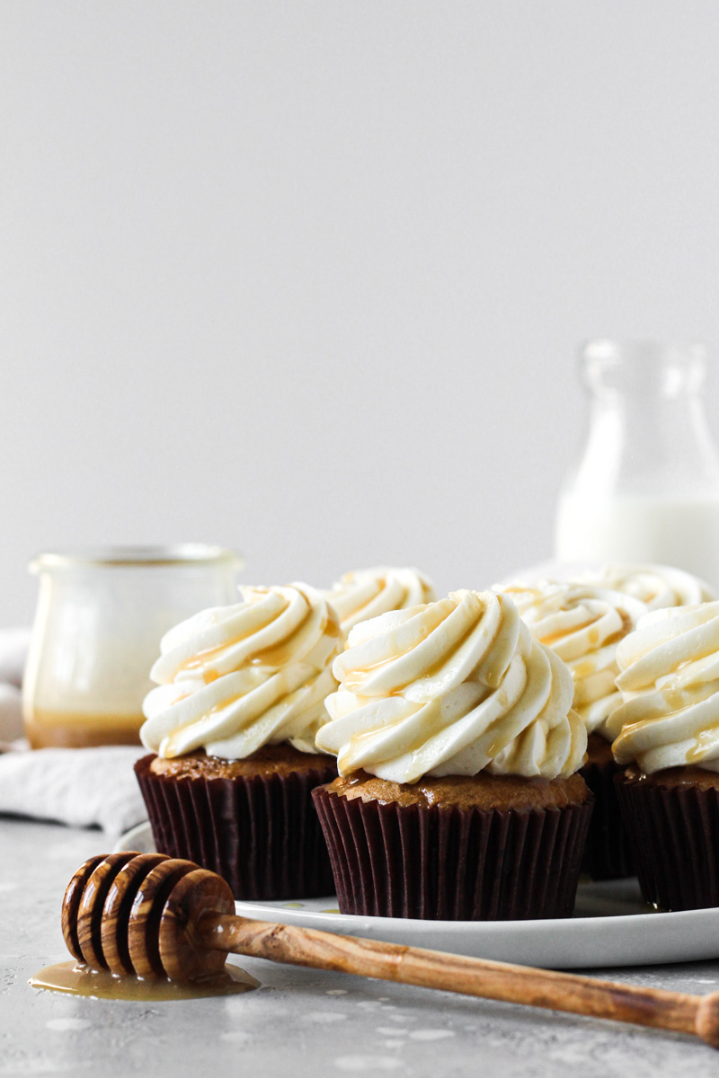 Plate of sweet potato cupcakes with salted maple caramel cream cheese frosting and a caramel drizzle.