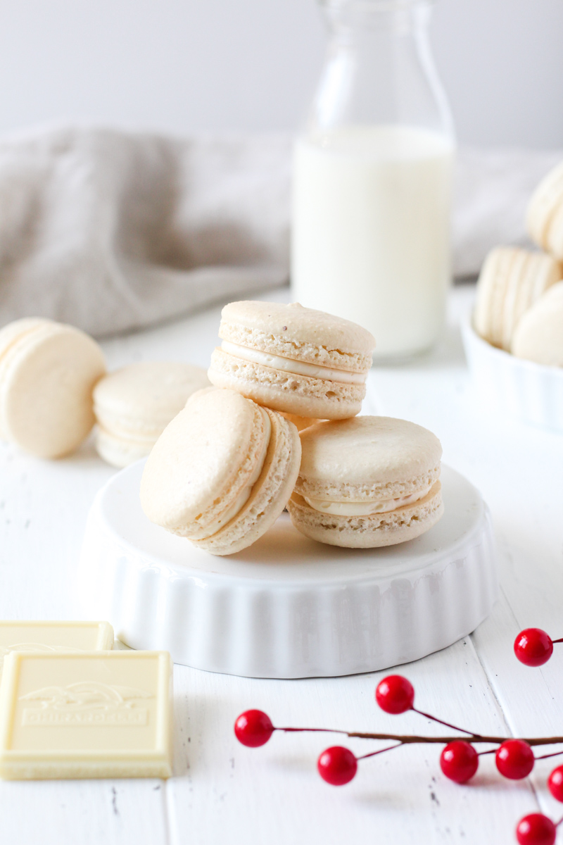 Stack of French macarons filled with cranberry sauce and white chocolate Swiss meringue buttercream on an upside down bowl.