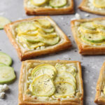 Individual baked puff pastry with feta, zucchini and yellow squash tarts.