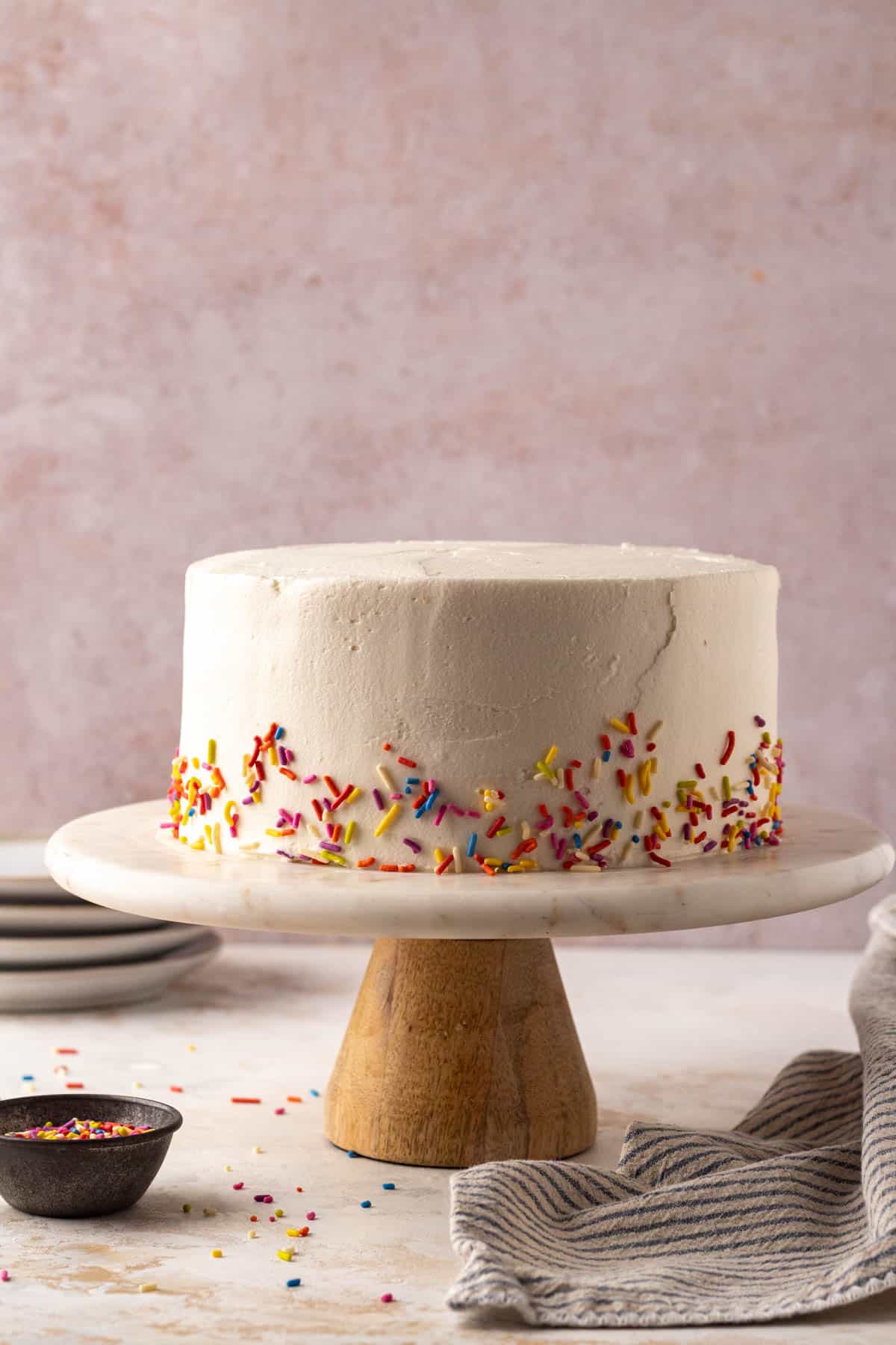 8 Inch cake on a cake stand with sprinkles around the bottom edges.