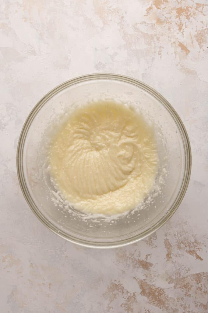 Creamed butter and sugar mixed with oil for vanilla cake in a mixing bowl.