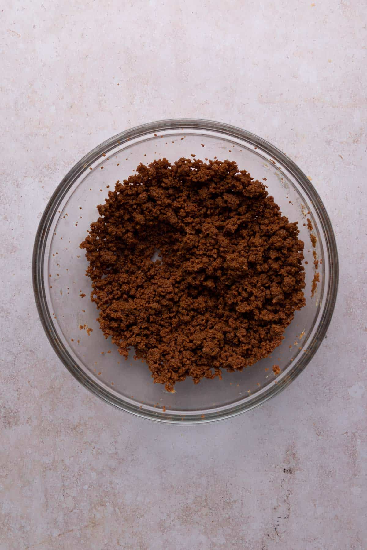 Biscoff cookie crumbs mixed with softened cream cheese and biscoff cookie butter in a mixing bowl.