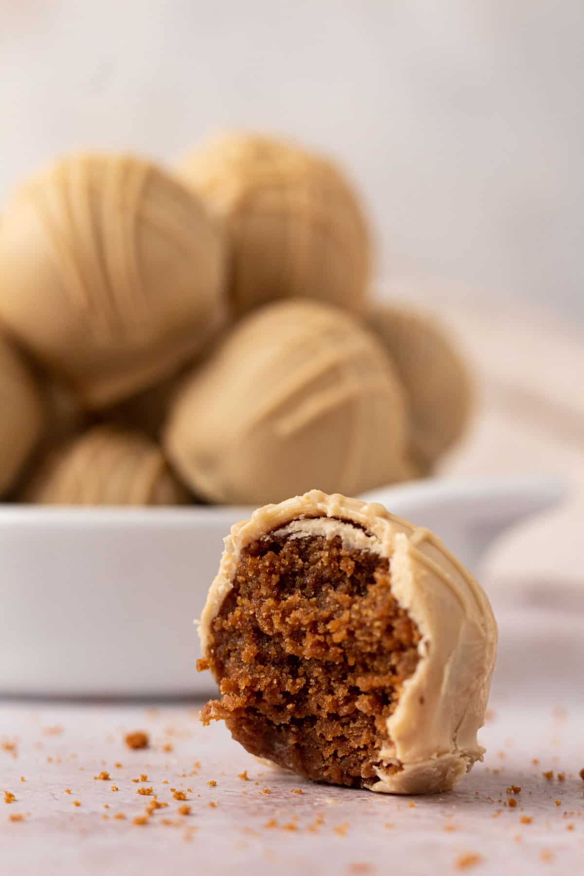Closeup of a cookie butter truffle with a bite taken out of it showing the interior and exterior white chocolate cookie butter coating.