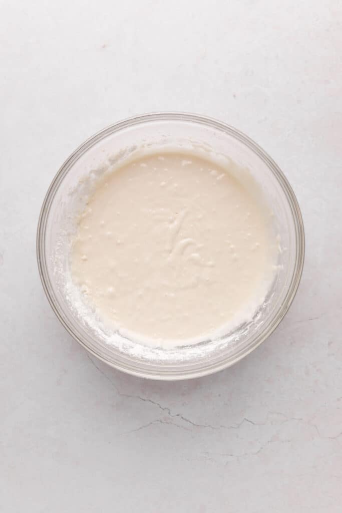 Mixing bowl of dry ingredients and milk added to strawberry cupcake batter.