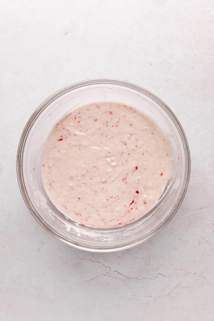 Mixing bowl of fresh strawberry puree mixed into strawberry cupcake batter.