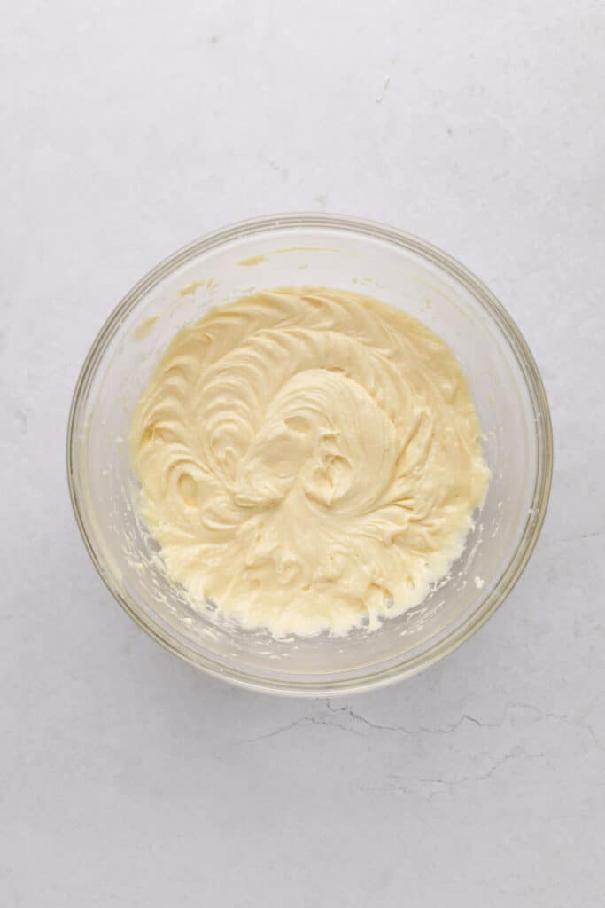 Mixing bowl of creamed sugar and butter with eggs and vanilla.