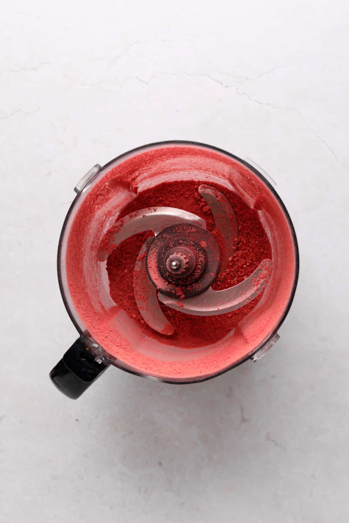 Food processor with processed freeze dried strawberries into a powder.