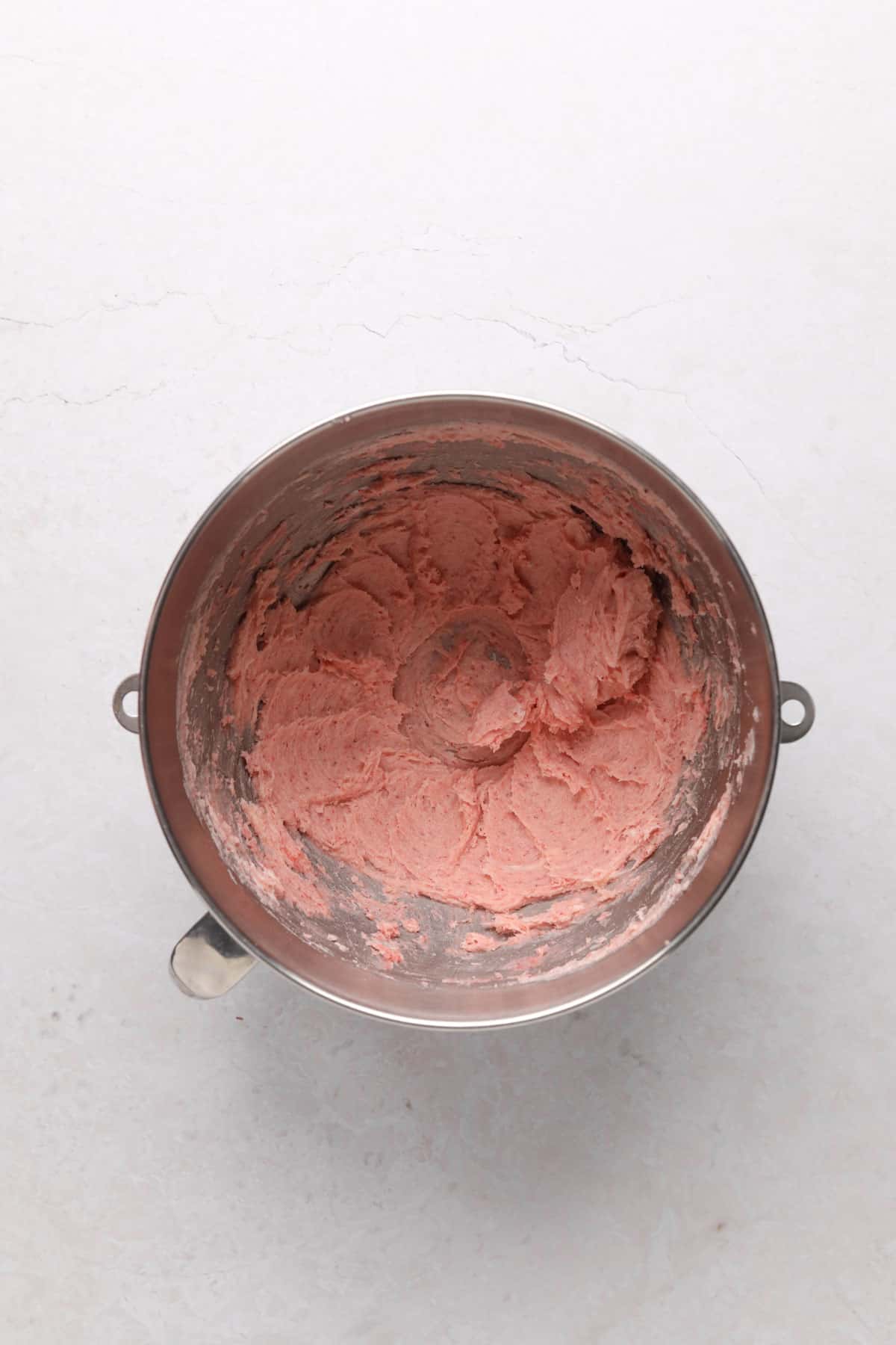 Stand mixer bowl with creamed butter, sugar, vanilla, and strawberry freeze dried powder.