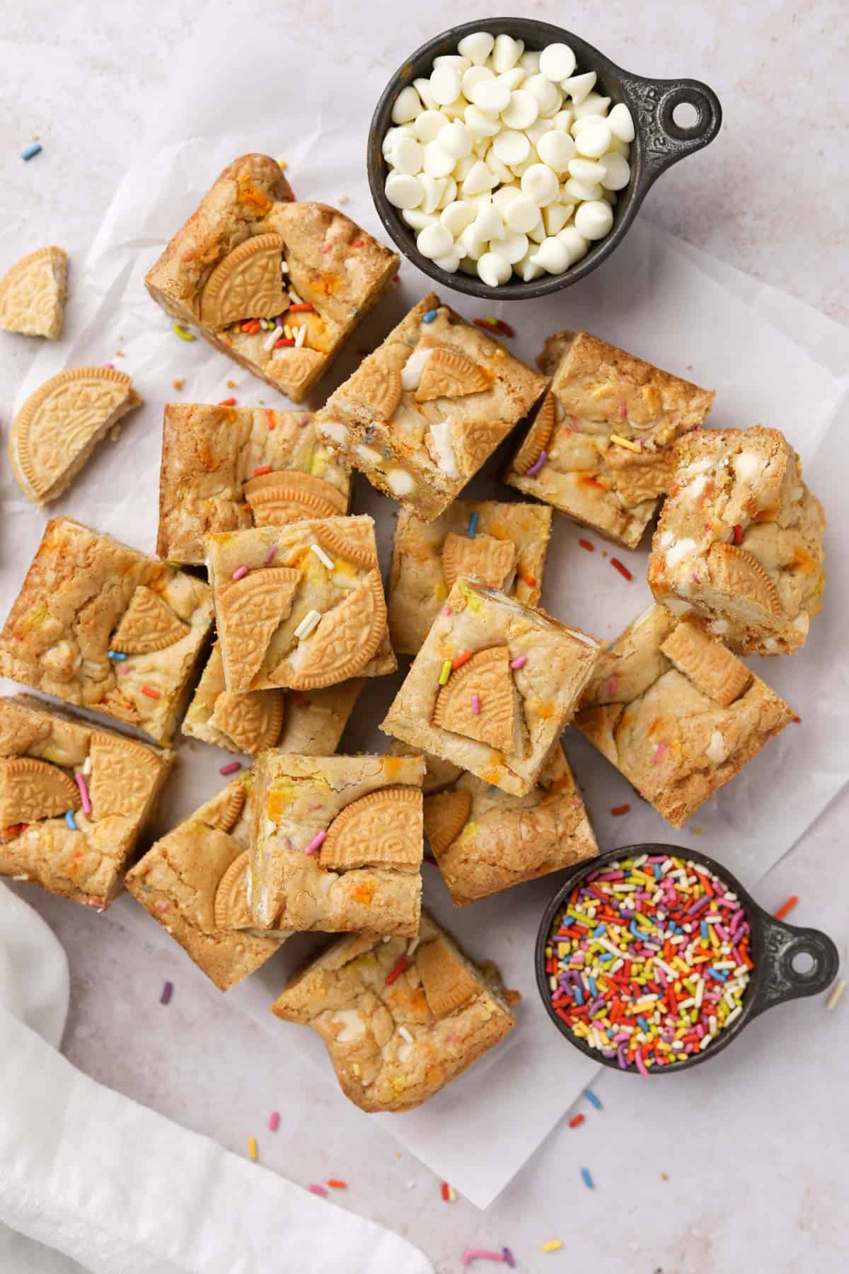Overhead shot of squares of birthday cake blondies with white chocolate chips and rainbow sprinkles.