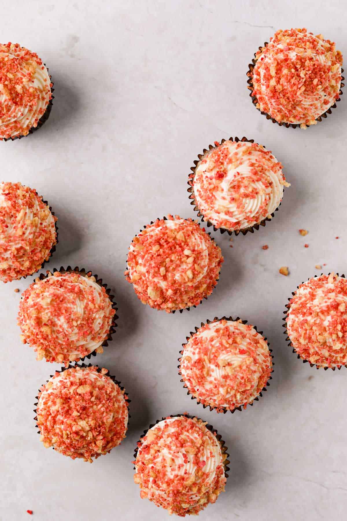 Overhead shot of strawberry crunch cupcakes with cream cheese frosting and strawberry crunch topping.