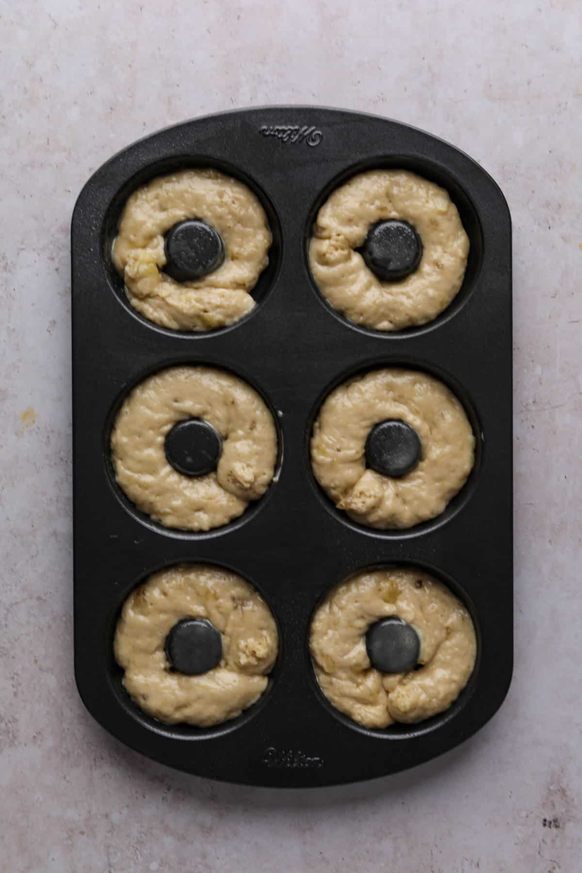 Banana donut batter divided into a 6 cavity non stick donut pan.