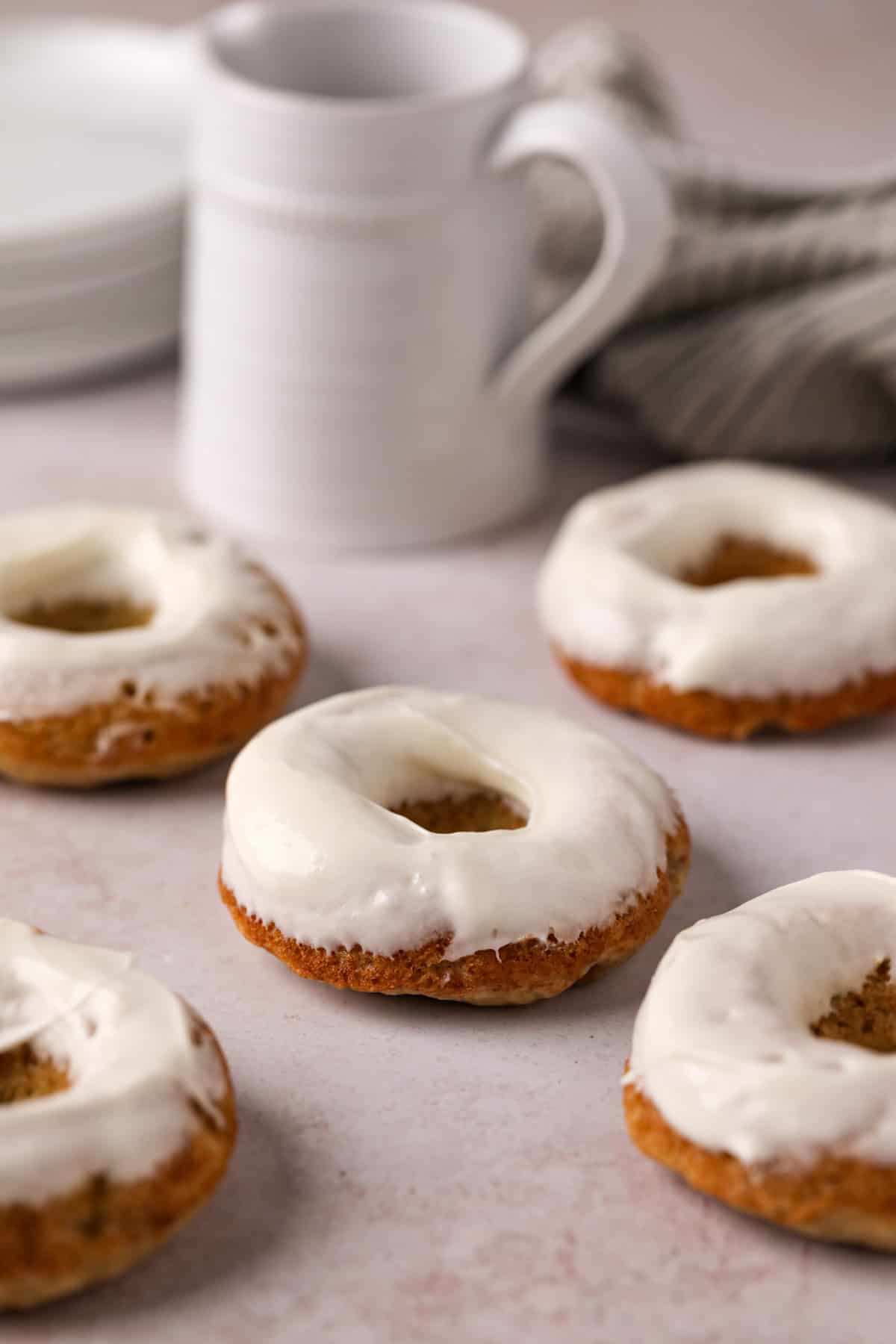 Cream cheese glazed baked banana donuts on a flat surface.