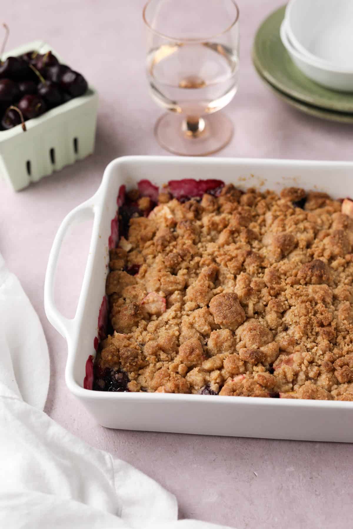 Baked cherry apple crumble in a white ceramic baking dish.