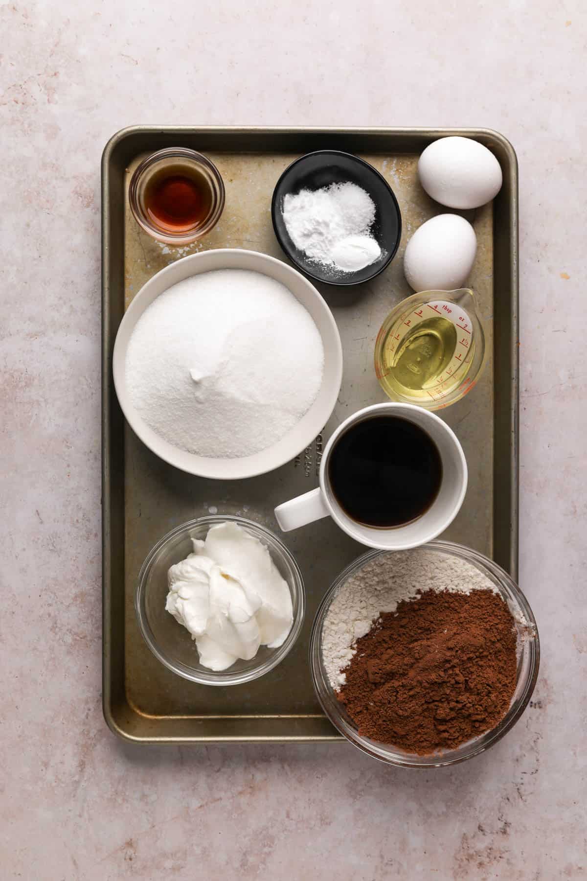 Chocolate fudge cake ingredients in bowls on a baking sheet.